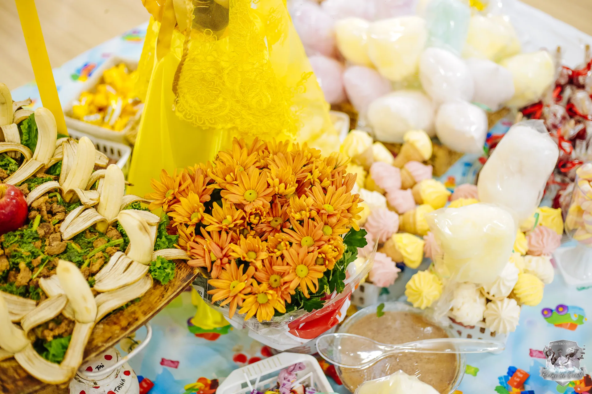 Mesa de Ibeji — oferendas com mel, doces e flores amarelas